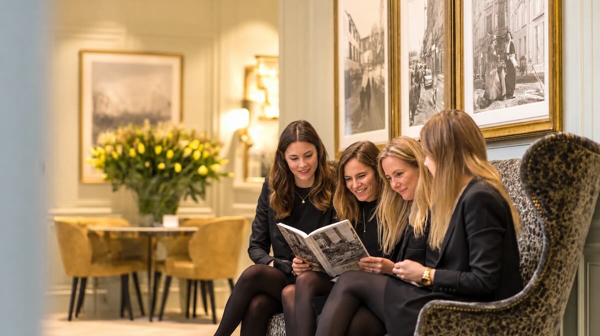 vier vrouwen bekijken een koffietafelboek in b5 formaat in exclusieve bedrijfsruimte - met tulpen op de achtergrond